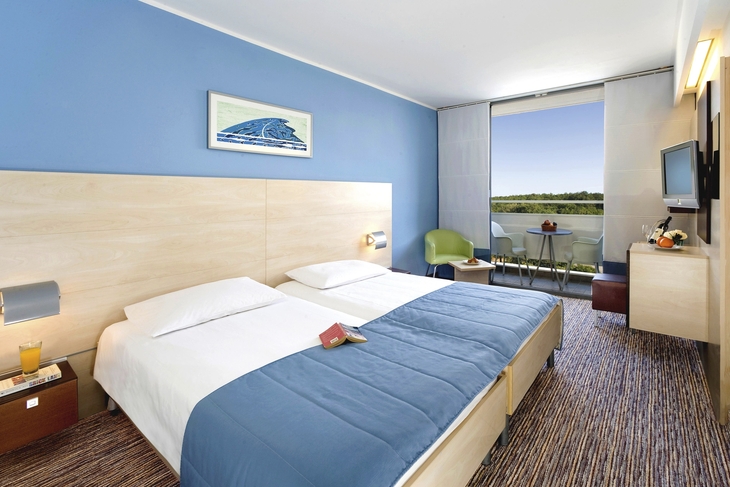 Hotelzimmer mit zwei Betten und Balkon mit Ausblick.