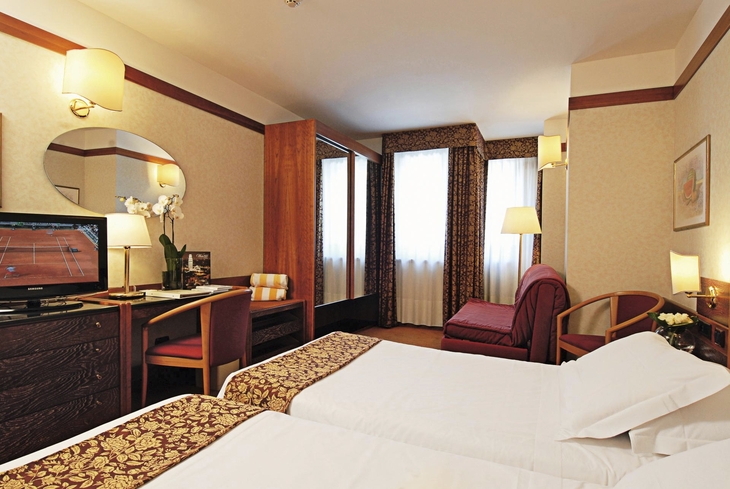 Komfortables Hotelzimmer mit zwei Betten, Schreibtisch und Fernseher.