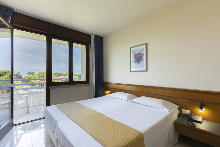Standard-Doppelzimmer mit Balkon, Blick auf den Garten und helle Einrichtung.