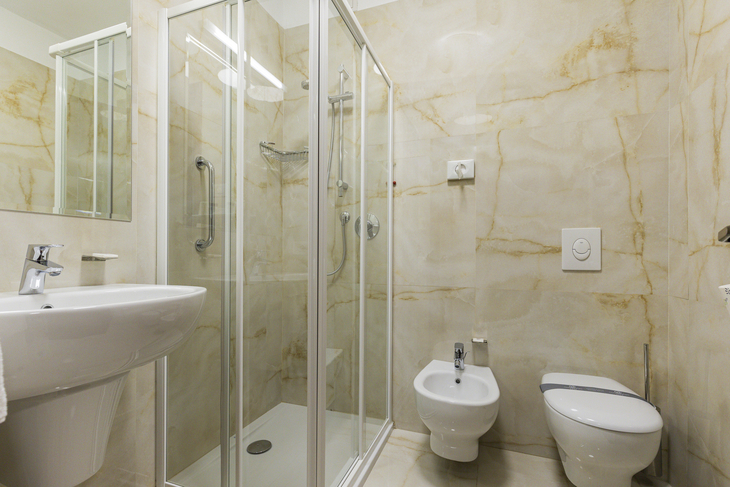 Modernes Badezimmer mit Dusche, Waschbecken, WC und Bidet in hellem Design.