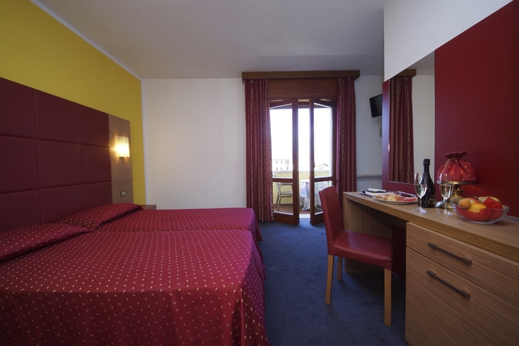Hotelzimmer mit zwei Betten, Balkon, Schreibtisch und Stühlen.