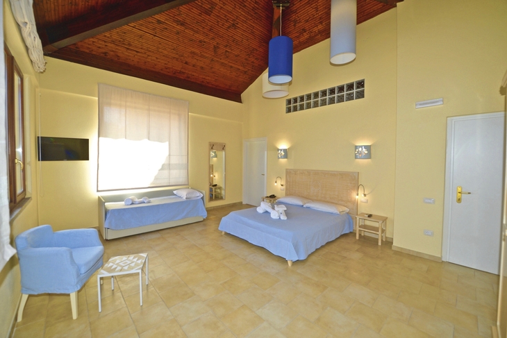 Geräumige Hotelsuite mit Doppelbett und Sofa, hell eingerichtet.