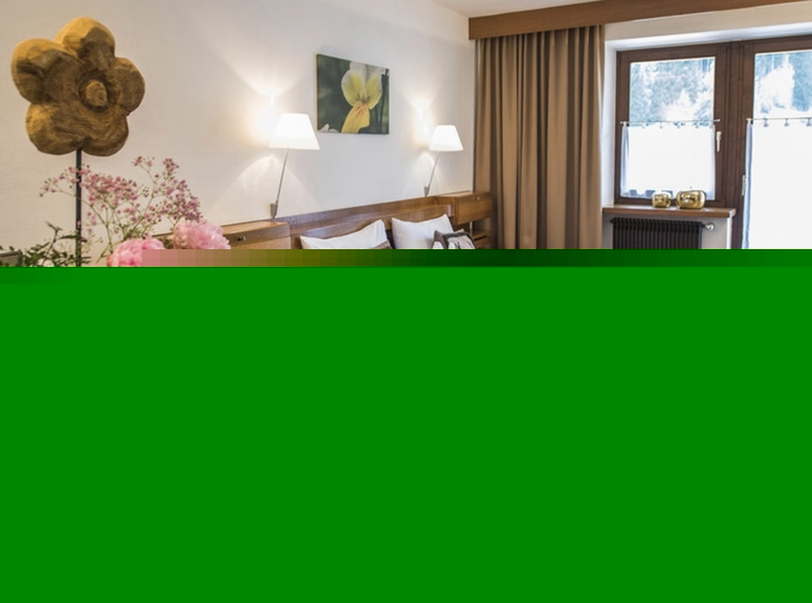 Gemütliches Hotelzimmer mit Doppelbett und Blumenarrangement.