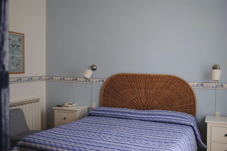 Hotelzimmer mit blauem Bett und geflochtenem Kopfteil.