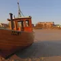 Holzboot am Strand von Ahlbeck bei Sonnenuntergang, Gebäude im Hintergrund.
