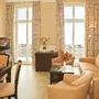 Helles Wohnzimmer mit Ledersofa, Esstisch und Blick durch große Fenster.