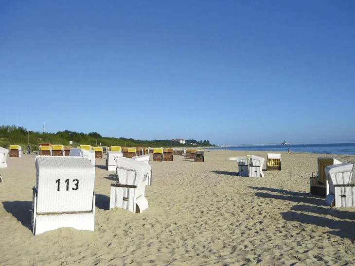 Strandkörbe am Sandstrand mit blauem Himmel im Hintergrund.