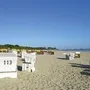 Strandkörbe am Sandstrand mit blauem Himmel im Hintergrund.