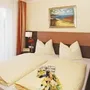 Doppelbett in modernem Hotelzimmer mit Bild an der Wand.