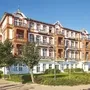Großes, historisches Gebäude mit roter Fassade in Ferienanlage, blauer Himmel.