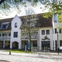 Ansicht eines Gebäudes mit roten Dachziegeln und weißen Fassaden im Sonnenschein.