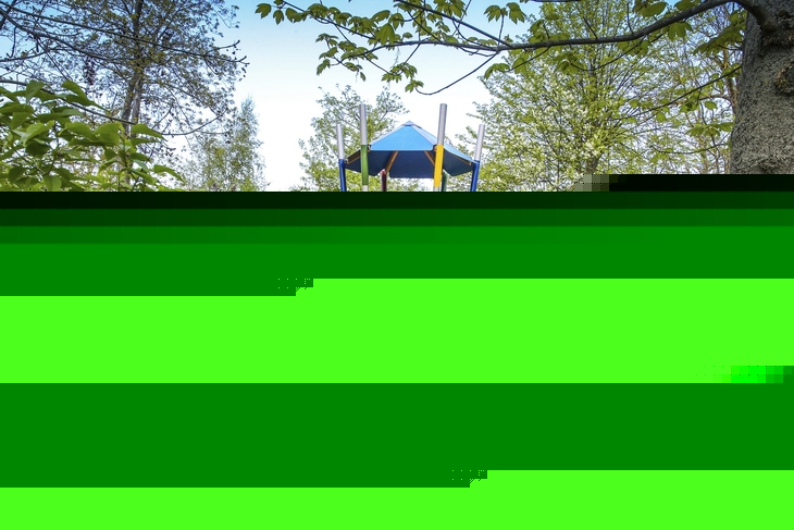 Spielplatz mit Kletterturm und Rutsche im Grünen.