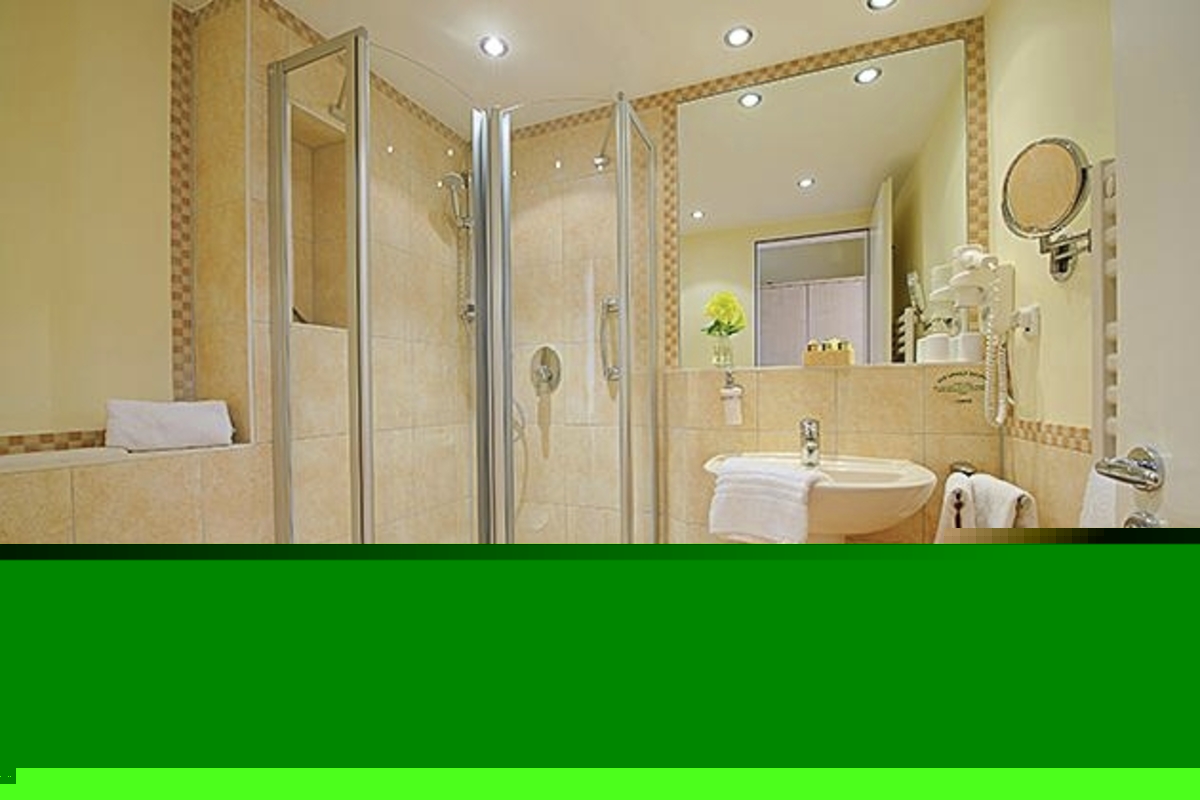 Modernes, helles Badezimmer mit Dusche, Waschbecken, Hocker, Handtüchern und WC, im Haus Oldenburg, in der Ferienanlage Timmendorfer Strand.