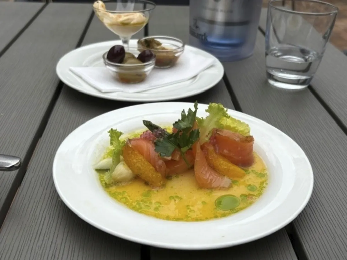 Vorspeise mit Lachs und Zitrusfrüchten auf einem Teller im Freien serviert.