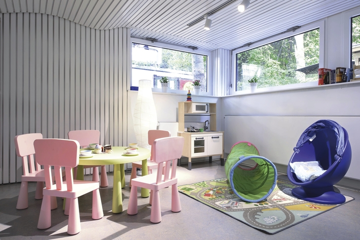 Spielzimmer in der Ferienanlage Timmendorfer Strand, mit Kindertisch und Kinderstühlen, Spielküche, Stofftunnel, Drehsessel und Spielzeug.