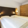 Doppelbett in einem gemütlichen Hotelzimmer mit Holzschrank und Nachttischen