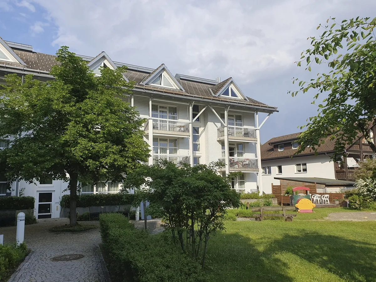 Ferienanlage mit Garten und Wohngebäude am Titisee bei Sonnenschein.