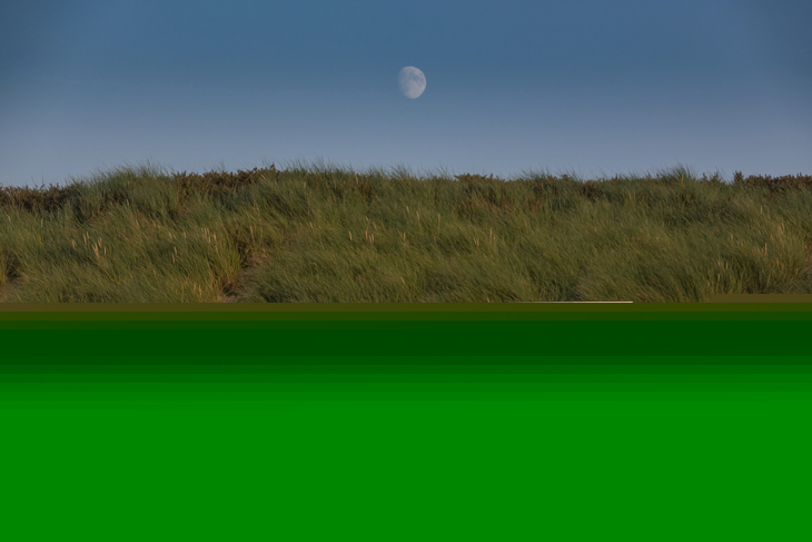 Zwei bunte Strandhütten bei Sonnenuntergang, Mond im Hintergrund.