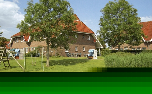 Backsteinhäuser mit roten Dächern und umgebendem Garten im Sommer.