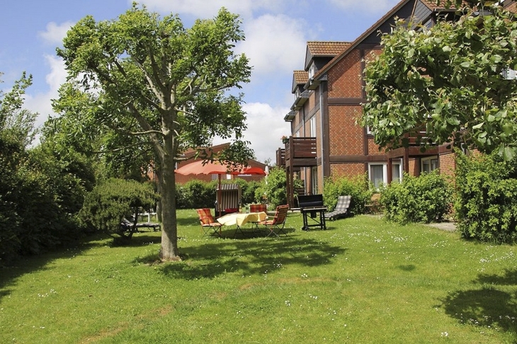 Ferienanlage mit Fachwerkgebäude und Garten bei Sonnenschein