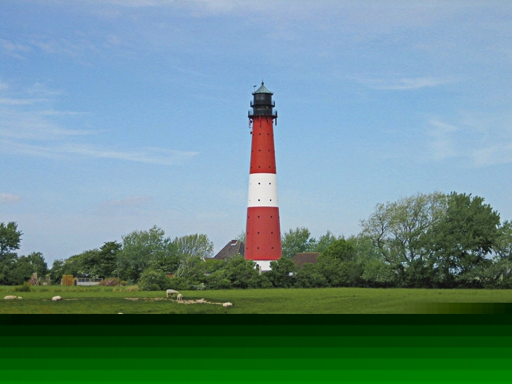Roter und weißer Leuchtturm im Grünen mit Schafen im Vordergrund.