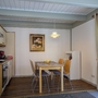 Essbereich mit Holztisch, vier Stühlen, einer Küchenzeile und einem Bild an der Wand.