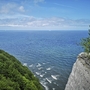 Blick auf das Meer von einer Steilküste mit grünen Bäumen im Vordergrund.