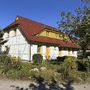 Ferienwohnung mit rotem Dach und gelben Akzenten in grüner Umgebung.