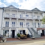 Historisches Gebäude mit Balkon und Geschäften im Erdgeschoss.