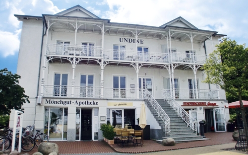 Historisches Gebäude mit Balkon und Geschäften im Erdgeschoss.
