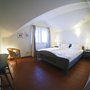 Helles Schlafzimmer mit Doppelbett und Schreibtisch, schlichte Dekoration.