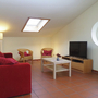 Wohnzimmer mit rotem Sofa, TV, Couchtisch und Dachfenster.