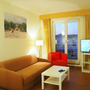 Wohnzimmer mit Sofa, Sessel, TV und Balkonblick in einer Ferienwohnung.