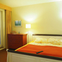 Helles Schlafzimmer mit Doppelbett, Nachttisch und Lampe in einer Ferienwohnung.