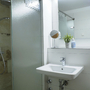 Bad mit Dusche, Waschbecken und Spiegel, modern und hell gestaltet.