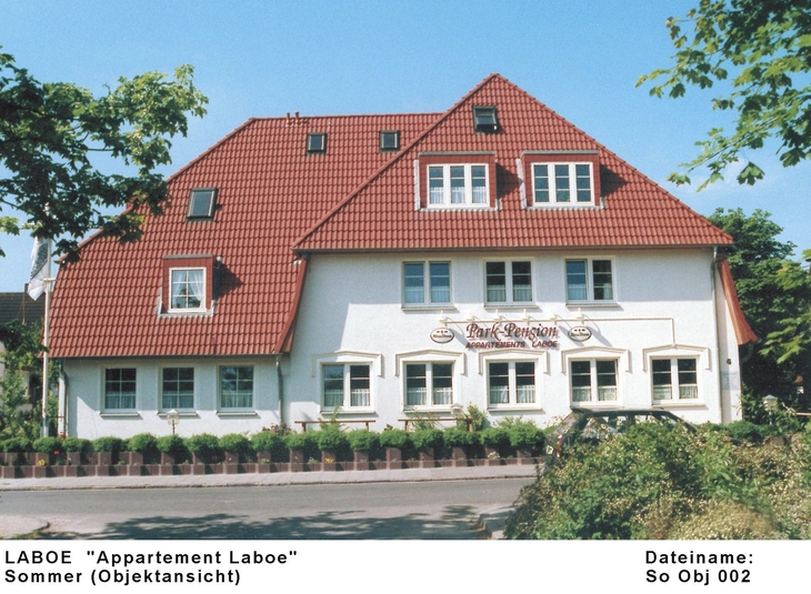 Zweistöckiges Haus mit rotem Dach und weißen Wänden in Laboe im Sommer.