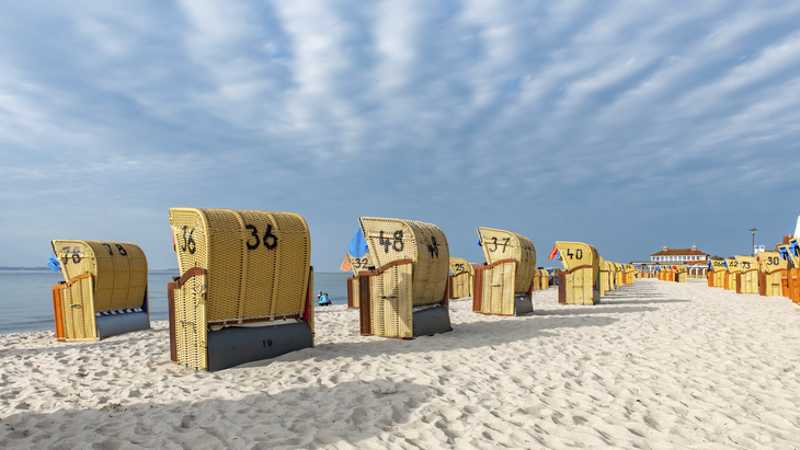 Strandkörbe am Sandstrand von Laboe unter bewölktem Himmel.