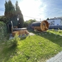Garten mit Sauna und Whirlpool, umgeben von Rasen und Bäumen.