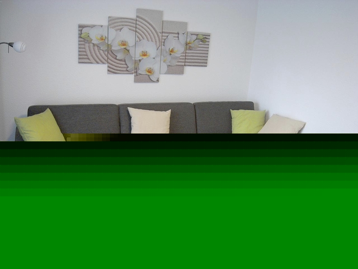 Graues Ecksofa mit Kissen und Couchtisch in modernem Wohnraum.