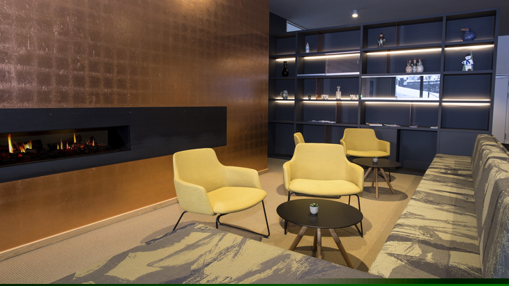 Moderne Lounge mit gelben Sesseln und Wandregal, Kamin an der Wand.