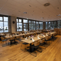 Speisesaal mit Holzstühlen und gedeckten Tischen, große Fenster, Blick ins Freie.