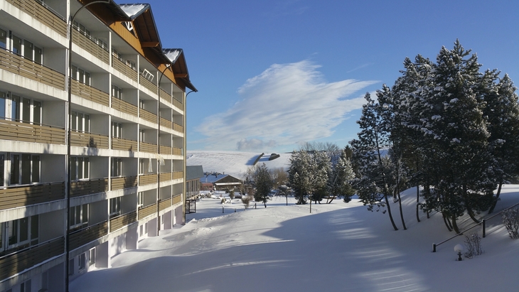 Verschneite Landschaft mit Gebäude und Bäumen bei klarem Himmel.