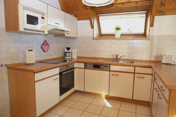 Küchenzeile mit Holzarbeitsplatte und Geräten in einem Ferienhaus.