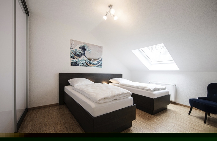 Zwei Einzelbetten in einem hellen Zimmer mit Dachfenster und Wandkunst.
