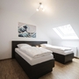 Zwei Einzelbetten in einem hellen Zimmer mit Dachfenster und Wandkunst.