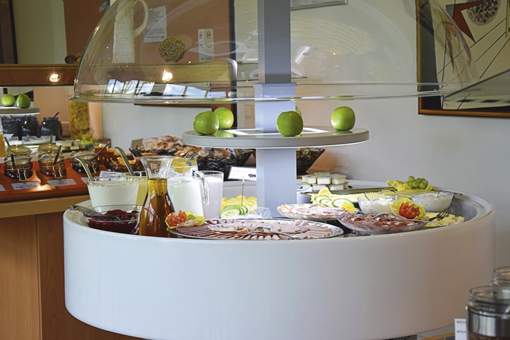 Frühstücksbuffet mit Aufschnitt, Getränken und grünen Äpfeln.