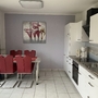 Moderne Küche mit Esstisch und roten Stühlen, Gemälde an der Wand.