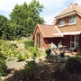 Backsteinhaus mit Garten und Terrasse bei sonnigem Wetter.