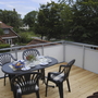 Terrasse mit Tisch und Stühlen, Blick auf Häuser und Bäume im Hintergrund.