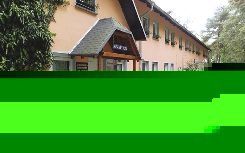 Eingang eines Appartementhauses mit Pflanzen und Gehweg im Feriendorf.